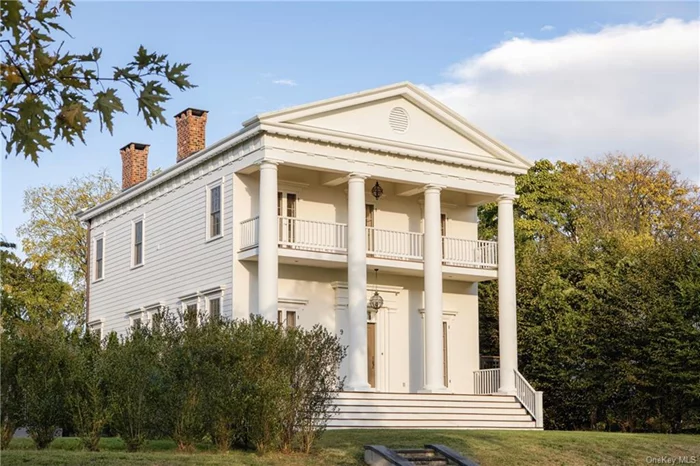 This striking Greek Revival home sits on a quiet road lined with ancient maple and oak trees, just along the peaceful outskirts of Hudson&rsquo;s historic district. Perched atop a grassy knoll, Willard Place has far-reaching views of the Catskill Mountains and some of the Hudson Valley&rsquo;s most vibrant sunsets.  Willard Place was built only twenty years ago yet was modeled perfectly after the stately Greek Revival homes so beloved among early 19th-century American architects. The front view of the exterior is quite dignified - four soaring Doric columns and classical cornicing are softened by a second-floor balcony and romantic French doors. A hidden driveway brings you to the fenced, brick-paved courtyard behind the home, where a diverse range of flowering bushes have been cultivated alongside giant evergreens.  The ground floor is thoroughly elegant, with soaring 12-foot ceilings,  epically tall Marvin windows, and rooms of grand proportions. Expertly curated light fixtures, primarily rare antiques collected over many years, are peppered throughout the home. Cozy, grounding touches come in the form of the home&rsquo;s two Egyptian-marble-clad fireplaces, its deep-colored Brazillian cherry floors, and solid, beautifully constructed mahogany doors. The kitchen, drenched in incredible sunlight each afternoon, is custom and handmade in Wiltshire by the British kitchen design studio Smallbone. A Lacanche range from their Vougeot line has a vertical warming cupboard and aged brass detailing. All appliances are Miele and discreetly built into the kitchen cabinetry. Completing the ground floor is a powder room adorned with Farrow & Ball wallpaper and glossy wainscoting.  The upstairs is light-filled and exceptionally peaceful. The expansive primary suite comprises half of the second-floor footprint and includes a sitting room, tucked-away sleeping alcove, and a master bath with built-in laundry. Three French doors with intricate brass hardware lead to the primary suite&rsquo;s balcony and the home&rsquo;s lush mountain views. A second guest suite with a full bath sits opposite the primary and is currently used as an upper-floor lounge room. The third bedroom is presently a flex office/guest space.  On a dead-end road surrounded by some of Hudson&rsquo;s most prominent historic homes, Willard Place perfectly balances town and country living. Just a few minutes from Warren Street, there is truly an endless amount of cultural, culinary, and creative offerings moments from your doorstep.