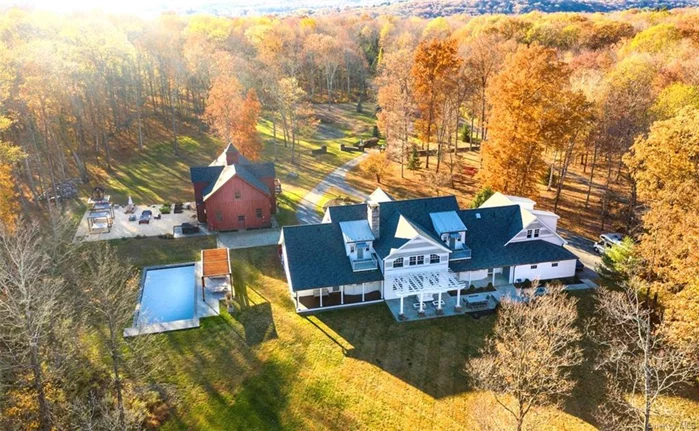 An extraordinary Union Vale estate brings together the craftsmanship of a master carpenter and the refined vision of a renowned NYC designer. Designed as a retirement masterpiece, the carpenter milled trees from the land, creating a barn with post-and-beam construction and intricate, nail-free joints. Over four years, the current owner has meticulously refined this home and barn, elevating it to over 9, 000 square feet of luxurious living space. Upon entry, guests are greeted by a two-story foyer, leading to a great room with soaring beamed ceilings, a gourmet kitchen, and a primary suite with a spa-like bathroom and private terrace. A finished basement adds functional elegance with designer tiling, a gym, and woodworking space. Outdoors, a 20 x 50 heated saltwater pool, an 8-person hot tub, and a cedar barrel sauna provide year-round relaxation. The Adirondack-inspired barn, fully insulated for year-round comfort, includes a rock climbing wall and adds 3, 500 square feet to the livable area. Set on nearly 10 acres, the estate is adorned with cherry blossoms, flower beds, and raised gardens, creating a serene natural retreat. Equipped with geothermal heating, radiant floors, and copper gutters, this sanctuary balances luxury and wellness in a private, exclusive community. Located just minutes from Millbrook Village, this estate offers a rare opportunity to own a residence where elegance and craftsmanship are seamlessly intertwined, creating a one-of-a-kind legacy for its fortunate next owners.