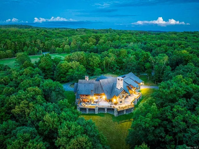 This timeless, Colorado lodge-style home is extraordinarily built and centered on 75+ acres in the heart of Millbrook. Located on one of Millbrook&rsquo;s country roads, close to the village. A gated entrance leads to this unique, 11, 500 square foot home constructed of standing dead timber from the west and immense stone from Pennsylvania. The colossal logs, which measure up to 41 inches in diameter, were cut and laid in place out west before being deconstructed and transported to its current location. The open floorplan lends itself to grand entertaining while offering enough niche areas to cozy-up in. At its center is a dramatic great room featuring a vaulted 32-foot ceiling and a mammoth fireplace that one can stand-up in. The wonderful chef&rsquo;s kitchen and adjacent full-size pub, den with fireplace and chess room add to the unique entertaining ambiance. There are five bedrooms suites which all open to their own private, covered porches. There are four full bathrooms plus three additional powder rooms. The kitchen boasts soapstone countertops and two sinks; and the 34&rsquo; x 17&rsquo; formal dining room can accommodate dinner parties for 30 people. Extending the space outdoors is a 2, 700 square foot deck with a huge outdoor stone fireplace and hot tub, all which can be accessed by most rooms on the first floor. The lower level features a game room with stone fireplace, an office with stunning mahogany built-ins, a soundproofed music room/recording studio, a professional soundproofed indoor shooting range, a mudroom, and a four-car tandem garage. Built in 2007, nothing was spared in the design and craftsmanship of this home including the 60 KW generator, built-in elevator shaft for a possible future addition, ventilation system in the lower level for enjoying an after-dinner cigar. The mechanicals are top-notch and include radiant heat throughout with 6 zones, Vantage lighting and alarm system, and a Creston sound system. This property also includes a barn and three ancillary residences perfect for overflow of guests, rental properties, or a caretaker. This is a rare opportunity to own the most unique property on the Millbrook market - perfect for the consummate sportsman or anyone who loves to entertain.