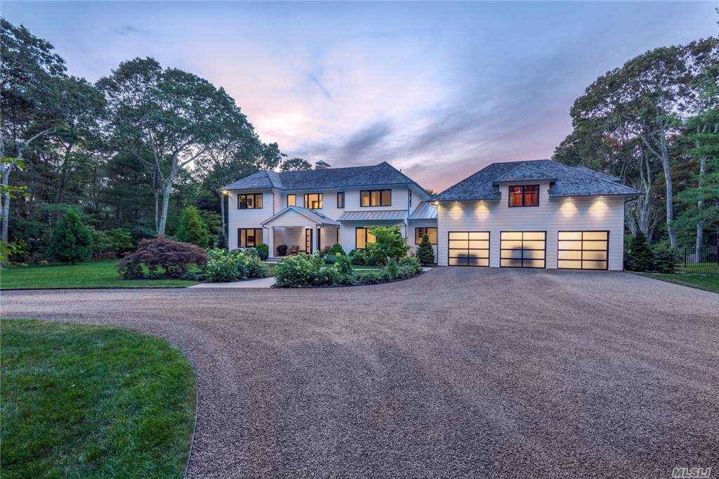  This Hamptons classic meets modern luxury, w/ all the finest comforts. in abundance, & a quicker trip to & from the city than any other on the East End. Newly constructed in 2019, the two-story board-and-batten manse is sited on 2.35 secluded, park-like acres w/ gated entry. Featuring top-of-the-line systems & amenities, the custom-designed 5,000-square-foot, five-bedroom, five-and-a-half-bath home includes custom heated saltwater Gunite pool; expansive outdoor entertaining areas; indoor & outdoor fireplaces; outdoor kitchen; outdoor shower; energy efficient building standards with HERS certification; & Miele appliances. The thoughtful design includes: first- and second-level primary-style bedroom suites; solar panels; a Generac generator; Sonos system; an irrigation well; radiant-heat flooring; walls of windows, including a NanaWall folding glass wall; chandelier lift; and ample parking, w/ three indoor spaces and an impressive circular drive.