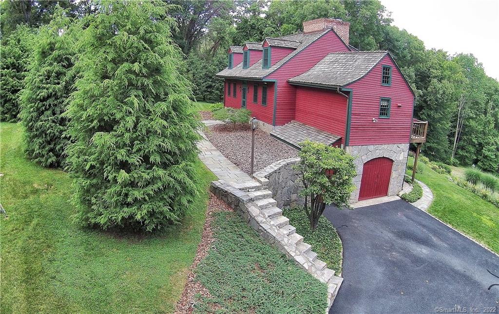 Quintessential CT retreat designed by notable historic restorer Ed Cady. One of Woodbury's last original post and beam homes, this 3 bed, 2.5 bath is the ultimate country escape. Located on one of the most sought-after streets, this hilltop modern farmhouse has spanning eastern and western views from every vantage point. Relocated in 1975, this charming home provides all the old world amenities including wide plank flooring, 4 brick fireplaces, and exposed hand hewn beams, yet still providing a desirable open floor plan. Upon entry, the original brick encased stairwell with a 4'x4' skylight leads to a sitting room with sliding barn doors, and a master bedroom suite with cathedral ceiling, many built ins, plaster coated walls and one of the four gorgeous brick fireplaces. The kitchen was renovated in 2021 and boasts custom cabinets with antique brass fixtures, Carrara marble kitchen island, quartz countertops, 8 burner Italian gas stove, commercial grade Viking hood and state-of-the-art stainless appliances.The upper deck was expanded in 2018 to accommodate an outdoor dining area and the lower deck, which leads to two additional bedrooms, family room & laundry, have floor to ceiling sliders which allow for year round enjoyment. Many exterior features including granite stone veneer around the foundation, antique stone steps. blue stone walls and a country landscape design. A custom Bocce Ball court and hilltop Adirondack lookout round out this truly special country retreat.