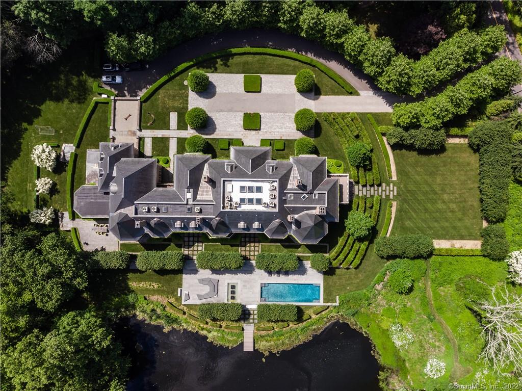 This European-style Chateau offers 18, 000 plus square feet and sits on over 6 acres in one of the finest suburbs in southern Connecticut just 60 min from NYC. Working with a local luxury builder, the owners focused on keeping the standards and aesthetics of grand European estates. To the left of the entrance is the music room which leads to a sunken octagonal shaped living room. Adjacent is the marble bar room, reading room, large office with sitting room, and two story library with freestanding glass bookshelves and a circular clear staircase leading down to the wine cellar and the master suite above. The right wing of the house features the large dining room and the contemporary kitchen/family room. The large sun filled gym has a full spa style bathroom. The second floor features a primary suite with oval bedroom, large sitting room, his and her bathrooms and closets. In addition, there are five large en suite bedrooms. The home offers seven bedrooms, nine full bathrooms and four powder rooms all with Porcelanosa tile and marble. The lower level is a showpiece with a remarkable wine cellar and game room, theater space and windows overlooking one of the most unique aspects of the house: the large underground car showroom, accommodating up to 24 cars. The landscape was designed by renowned landscape architects Doyle Herman Associates. The grounds also feature beautiful terraces and fountains, a tennis court, and a swimming pool that overlook the pond.