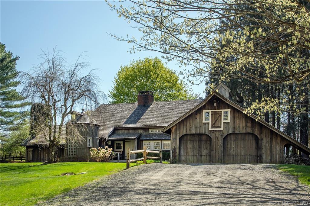 Goose Gate Farm - Romantic converted dairy barn relocated from New York State with original antique beams, rugged timbers and natural woods evoking the feeling of tranquility. The center fireplace welcomes you into the spacious foyer with a vaulted ceiling and plenty of room for a pair of overstuffed chairs. On the other side of the large fireplace, facing southwest, is the lofty great room with impressive cathedral ceilings combining the library, living room and dining room. Charming details include built-ins, french doors to the rear deck and wood burning floor to ceiling fireplace composed of brick. Buttery wide board floors carry throughout the house. The kitchen includes an island, breakfast bar, pantry, plate room and a convenient mudroom with butler's pantry and half bath leading to the attached two bay garage. The primary bedroom is located on the main level and includes a fireplace, full bath, built-ins and french doors opening onto the rear deck. The upper level is made up of two bedrooms, one with a sitting room area, both with skylights, and one full bath. Beautifully landscaped with specimen trees and enormous evergreens. Stunning western views overlooking the level park-like grounds and adjacent protected land. Sought after quiet Washington location on beautiful Shearer Road amongst lovely country properties. 90 minutes from NYC.