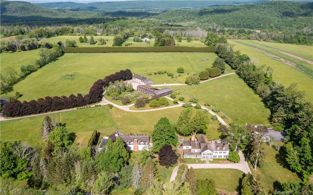 Iconic Sharon showcase estate now available on ~35 park-like acres with stunning panoramic views. (This listing now includes additional 10+ acres with 2 BDR house, pond, and building site). This enchanting property (main house c. 1870) was transformed into a magnificent country compound, combining old world charm with modern amenities. The 5 BDR, 6.5 Bath main house reflects the grandeur of its original vintage - gracious rooms and 7 fireplaces. A circular drive leads to a grand entry with fireplace, living room with fireplace and large windows. Formal dining room features an elegant marble fireplace and French doors, leading to an enclosed east-facing sunporch. Spacious kitchen and breakfast room with large hearth and antique beams. Elegant wood paneled study with fireplace & bar connects to adjoining pool house with 3 BDR, 3 Bath guest quarters and entertainment space. Impressive field stone fireplace, cathedral wood-beam ceilings, and enclosed terrace. Gym, sauna, and pistol range on lower level. Beyond the gardens and apple orchard: 8 stall horse barn with attached car barn with lift, large equipment barn, antique storage barn, riding paths, guest house, greenhouse, and tennis court. Across from 70+ acres of Sharon Land Trust (Benton Hill Preserve) with fabulous hiking trails. Ideal for the car collector with space for 20+ cars. 15 minutes to Lime Rock Park! Stately setting, minutes to town and under 2 hours to NYC. Close to area Private Schools, Troutbeck and Train.