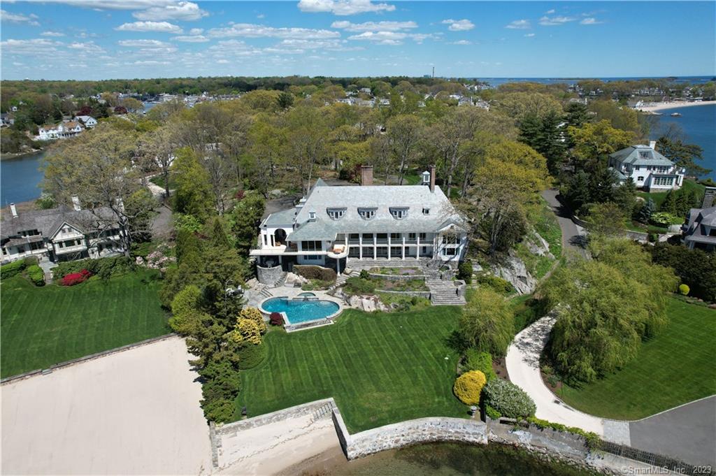 DON'T MISS VIDEO at top! From a natural 32ft stone bluff high above the sea, with 2.79 private acres sits this waterfront home on the exclusive peninsula of Butler's Island. In the private Tokeneke Association, the brilliant & bold design of this 8500SF, 7 BR, 8 BTH home came from the collaboration of architect Dean Telfer & the owner with the goal of creating a home of 180 degrees of sweeping southwesterly facing views of Long Island Sound. Entering through the stone courtyard, past the KOI pond, through the foyer, you are awed by the breathtaking vaulted barrel shaped wooden ceiling, light colored woods & a feeling of harmony in the LR & wall of glass windows & doors leading to the sea and the covered stone terraces. The kitchen connects to the FR, also glass overlooks the sea. The guest suite w/private patio. The opposite wing houses the huge vaulted primary suite with double baths, closets & a view of LIS which leaves you breathless. There are two other en-suite BR & a mahogany paneled LIB w/ fpl. The lower level with fpl, big bar, gym with full bath & sauna. Add a large guest suite & sitting room, a beautiful glass office with a connecting poker room, & open your doors to the terraced walkways & a level manicured lawn which sweeps you to your own sandy beach & infinity pool. For more entertainment, the 3rd floor as a 31x27 media room, billiards room, two more BRs, and a doll house room. 3-car garage. Beaches, sun, privacy, but above all, it is the VIEW!